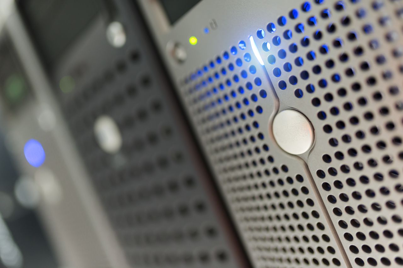 services-01 Focused detail of a modern server rack with blue LED indicators in a data center.